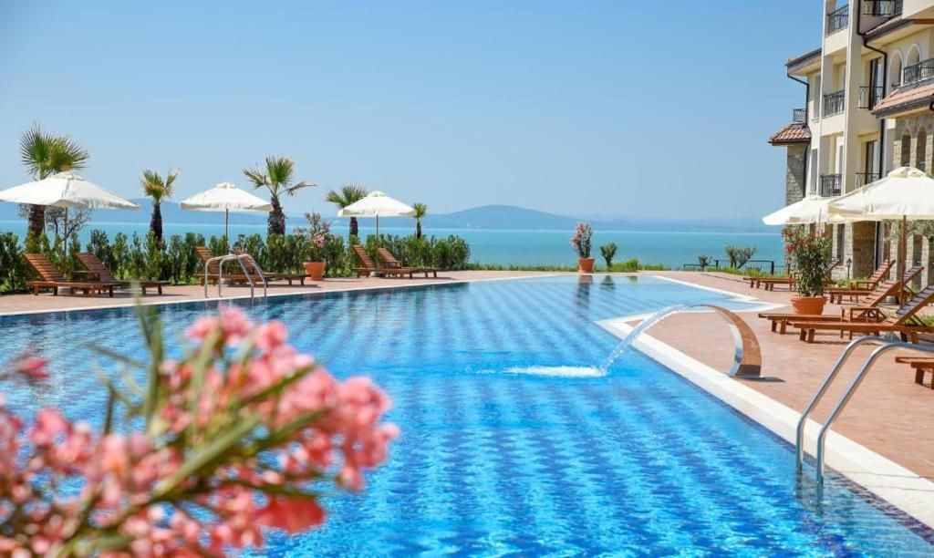 A swimming pool with lounge chairs and umbrellas, overlooking a body of water.
