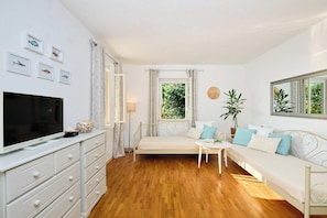 A bedroom with a bed, a TV, a dresser, and a window with curtains.