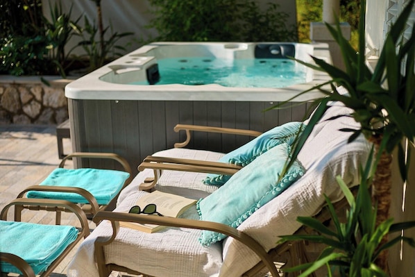A hot tub with lounge chairs and towels, surrounded by plants.