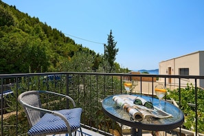 A balcony with a round table, two chairs, a book, and two glasses of orange juice. - House Lillla (Dubrovnik)