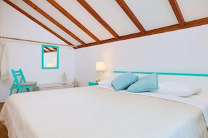 A bedroom with a bed, a chair, a nightstand, a lamp, and a mirror.