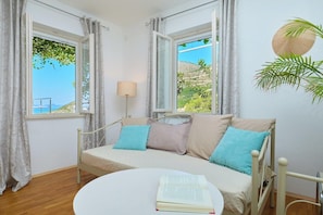 A room with a bed, a round table, and two windows with curtains.