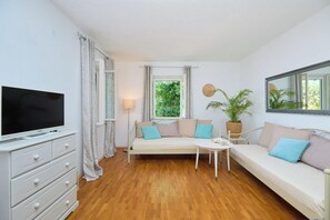 A modern living room with a flat-screen TV, a sofa, a small table, and a potted plant. - House Lillla (Dubrovnik)