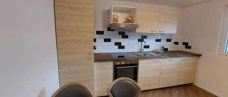 A modern kitchen with wooden cabinets, a black and white tiled backsplash, and a built-in oven.