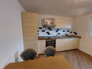 A modern kitchen with wooden cabinets, a black and white tiled backsplash, and a built-in oven. - Good Bed Wynau (Wynau)