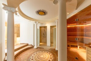 A grand hallway with a circular mosaic floor, white columns, and a wooden wall with a built-in sauna. - Appartement Suiten Hotel Glv Cknerin (Untertauern)