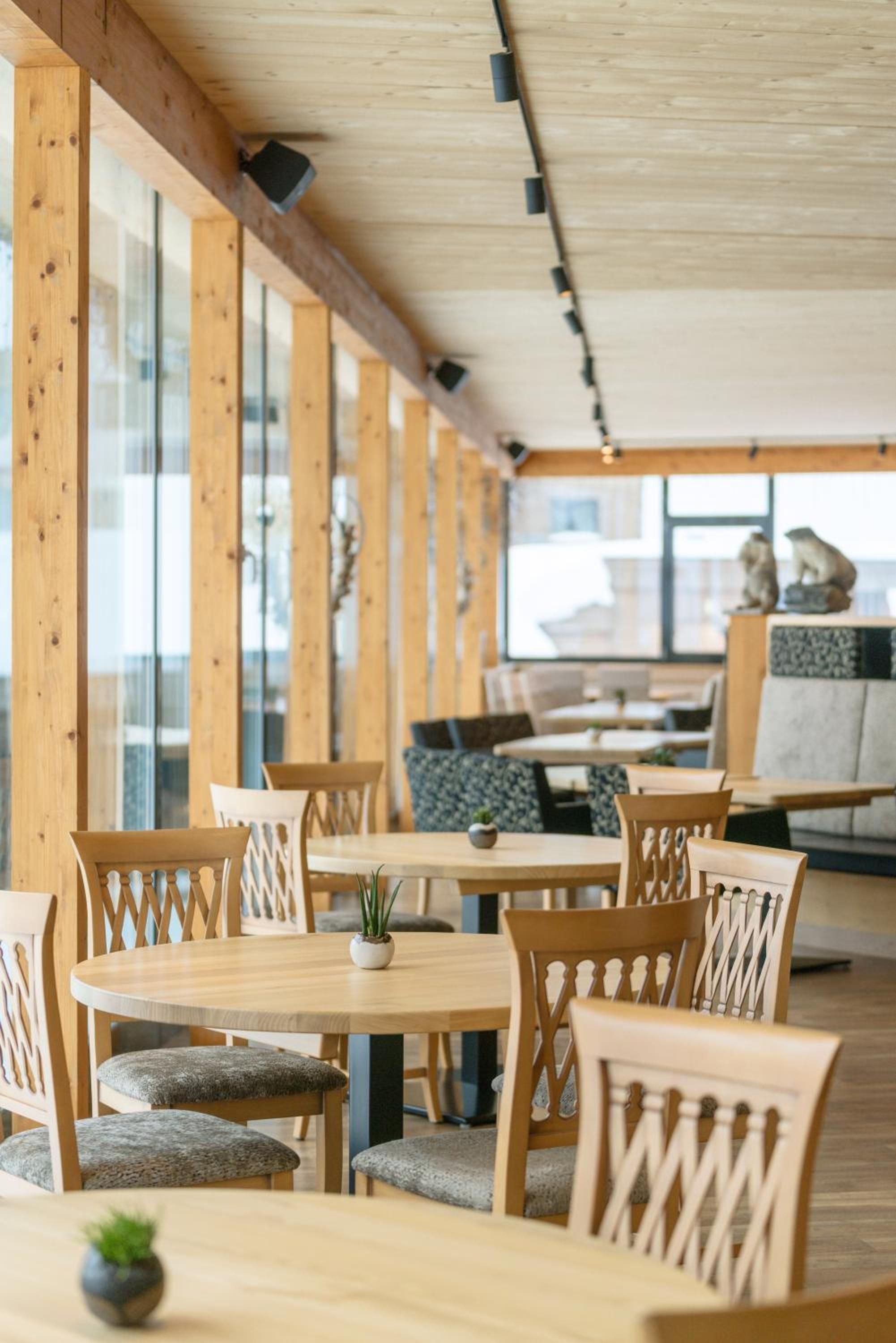 A restaurant with wooden tables and chairs, large windows, and a view of the city.