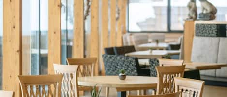 A restaurant with wooden tables and chairs, large windows, and a view of the city.