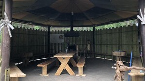 Un pabellón al aire libre con una mesa y bancos, rodeado por una valla de madera.
