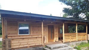Una cabaña de madera con un porche, una puerta y una ventana.