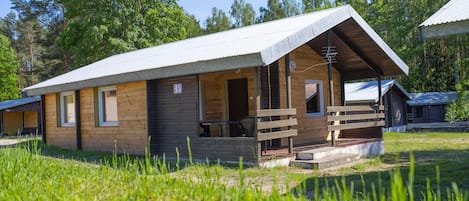 Eine Holzhütte mit einem Metall-Dach, einer Veranda mit Bänken und einem Nummernschild, das den Standort angibt.