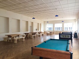 Amplio espacio interior con mesa de billar, bancos de madera y mesas.