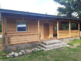 Una baita di legno con veranda, una porta e una finestra.