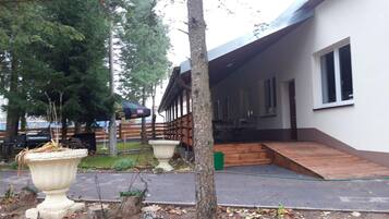 A building with a covered porch, a wooden deck, and a paved walkway.