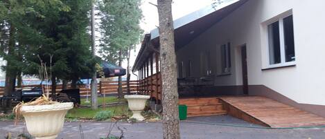 A building with a covered porch, a wooden deck, and a paved walkway.