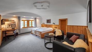 Une pièce comprenant un lit, un bureau, une chaise, une table ronde et un canapé.