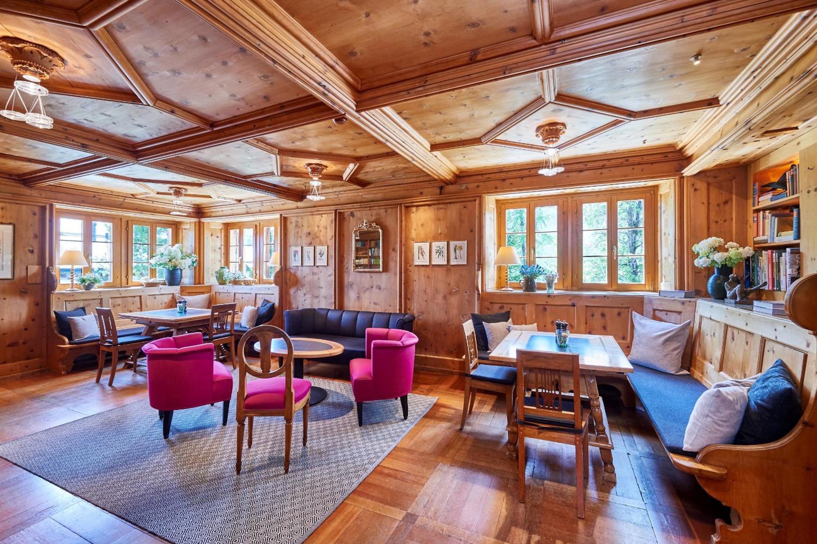 A wooden interior with a dining area, seating, and bookshelves.