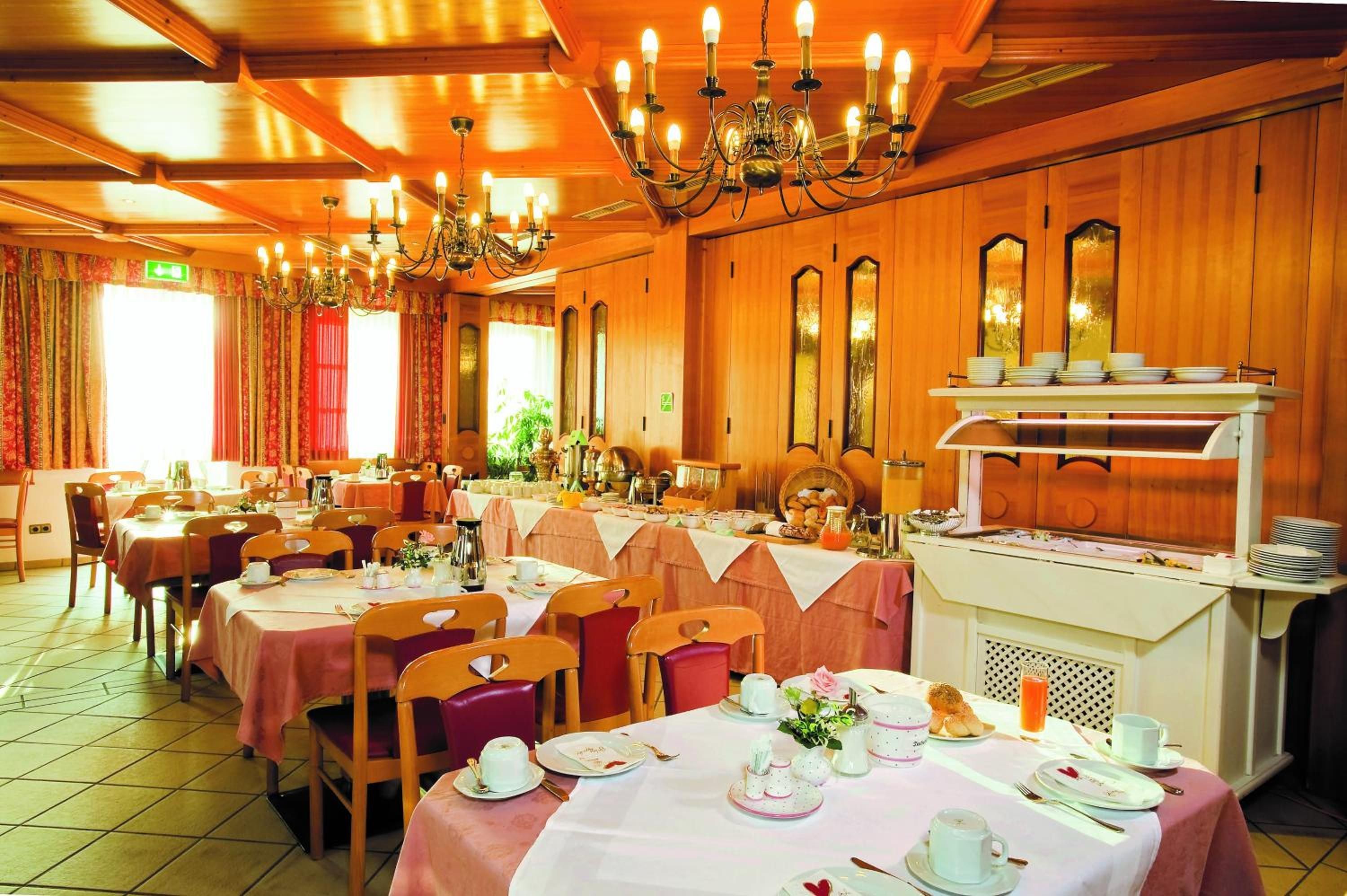 Ein Restaurant mit mehreren Tischen, Stühlen und einem Buffetbereich.
