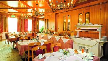 Ein Restaurant mit mehreren Tischen, Stühlen und einem Buffetbereich.