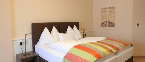 A hotel room with a bed, bedside table, lamp, and a wall-mounted artwork.