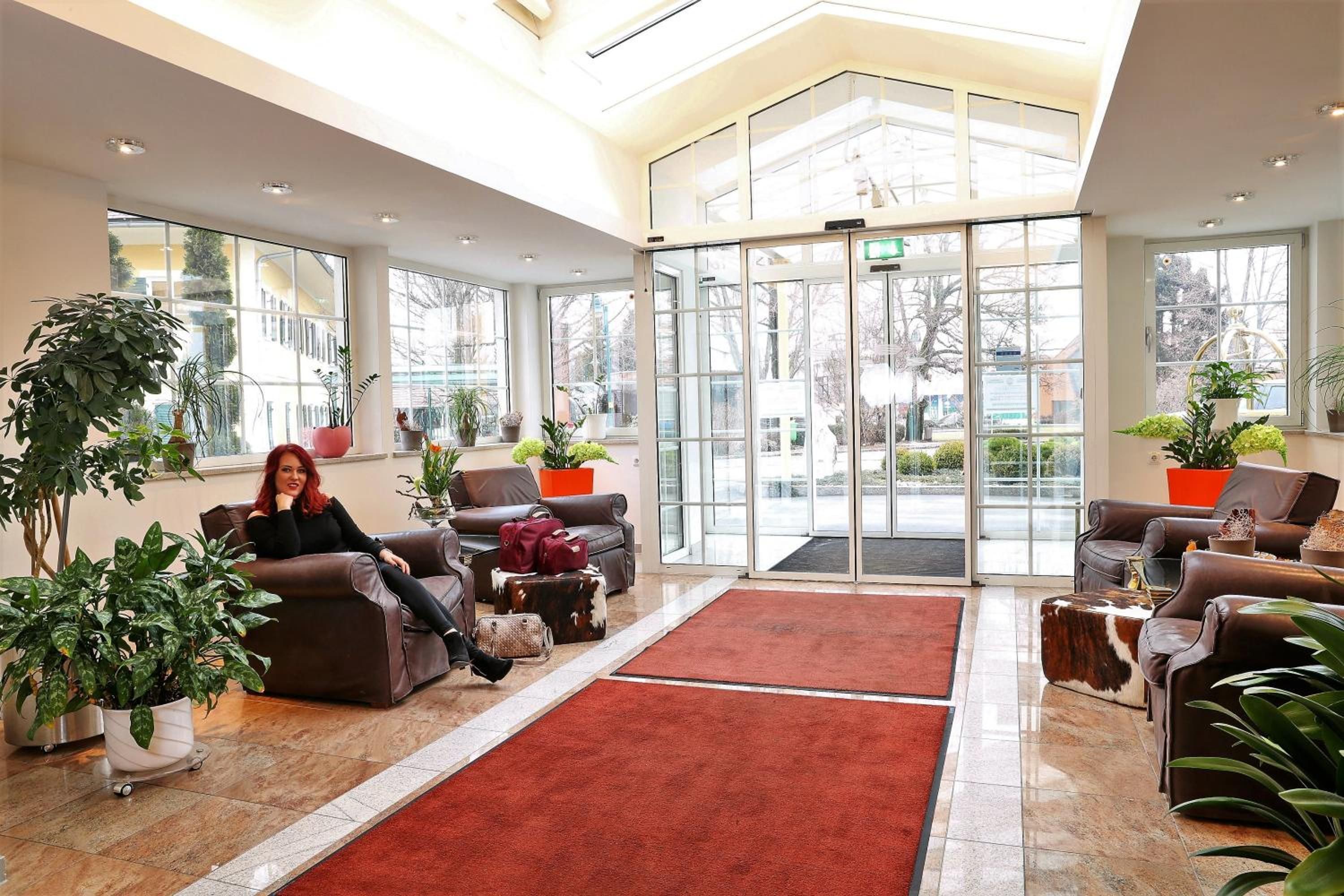 A spacious lobby with leather sofas, a red carpet, and potted plants.
