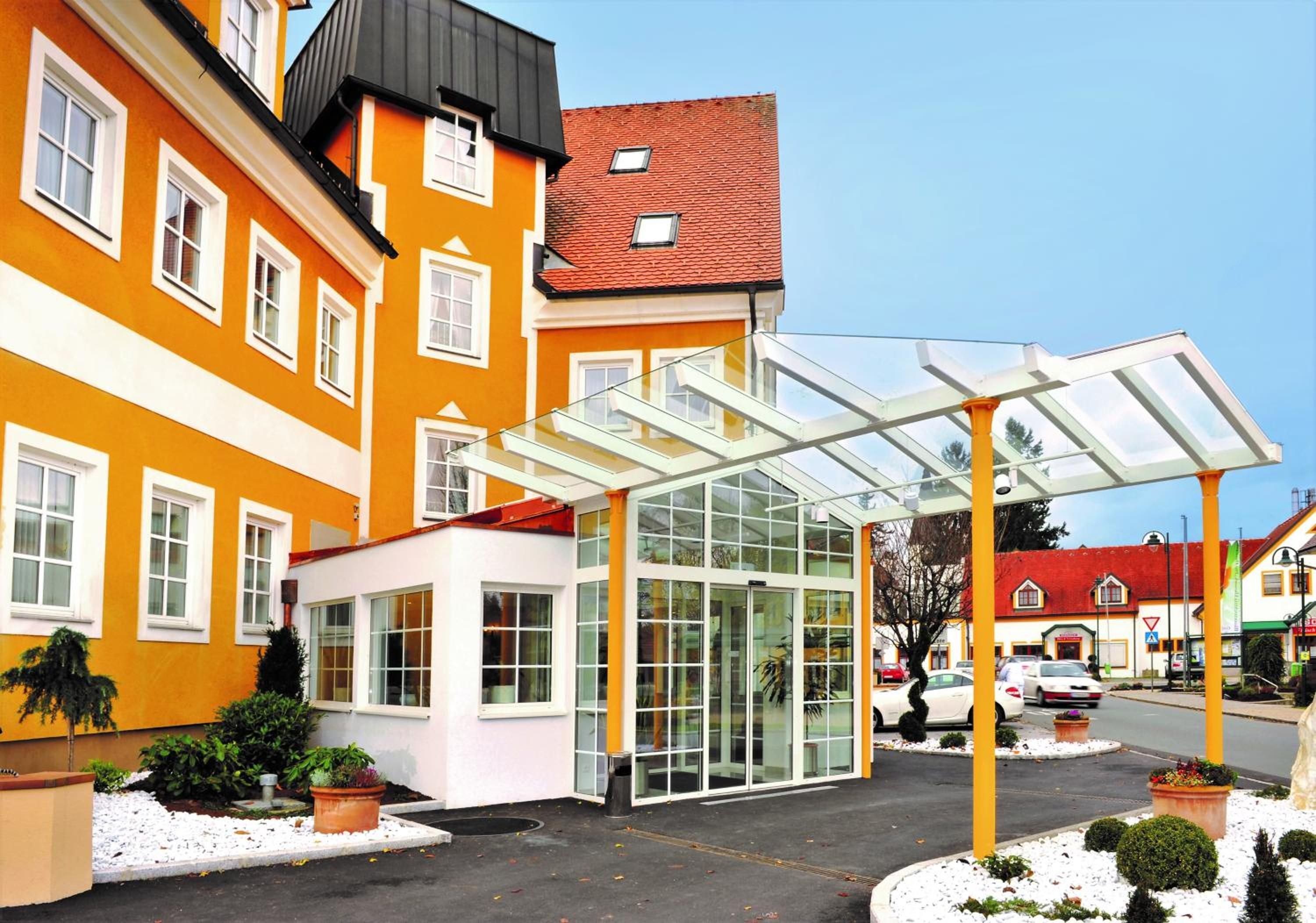 Entrada de hotel con un invernadero de cristal, un edificio con techo rojo y suelo cubierto de nieve.