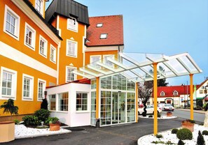 A hotel entrance with a glass conservatory, a red-roofed building, and a snow-covered ground. - Sorgerhof (Frauental an der Lassnitz)