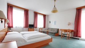 Una habitación de hotel con cama, escritorio, silla, sofá y televisor.