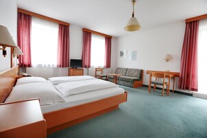 Una habitación de hotel con cama, escritorio, silla, sofá y televisor.