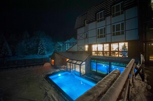 Un edificio moderno con piscina cubierta de cristal y otro edificio con el interior visible.