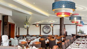 Un restaurante con varias mesas y sillas, una araña de cristal y una obra de arte colgada en la pared.