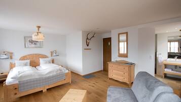 Een slaapkamer met een houten bed, een nachtkastje, een dressoir, een grijze bank en een houten salontafel.