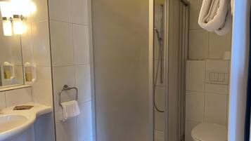 Een badkamer met een douchecabine, een wastafel, een toilet en een handdoekhouder.