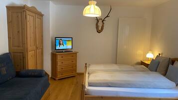 Een slaapkamer met een houten bed, een televisie op een dressoir, een houten garderobe en een decoratieve decoratie van een hertenschut.