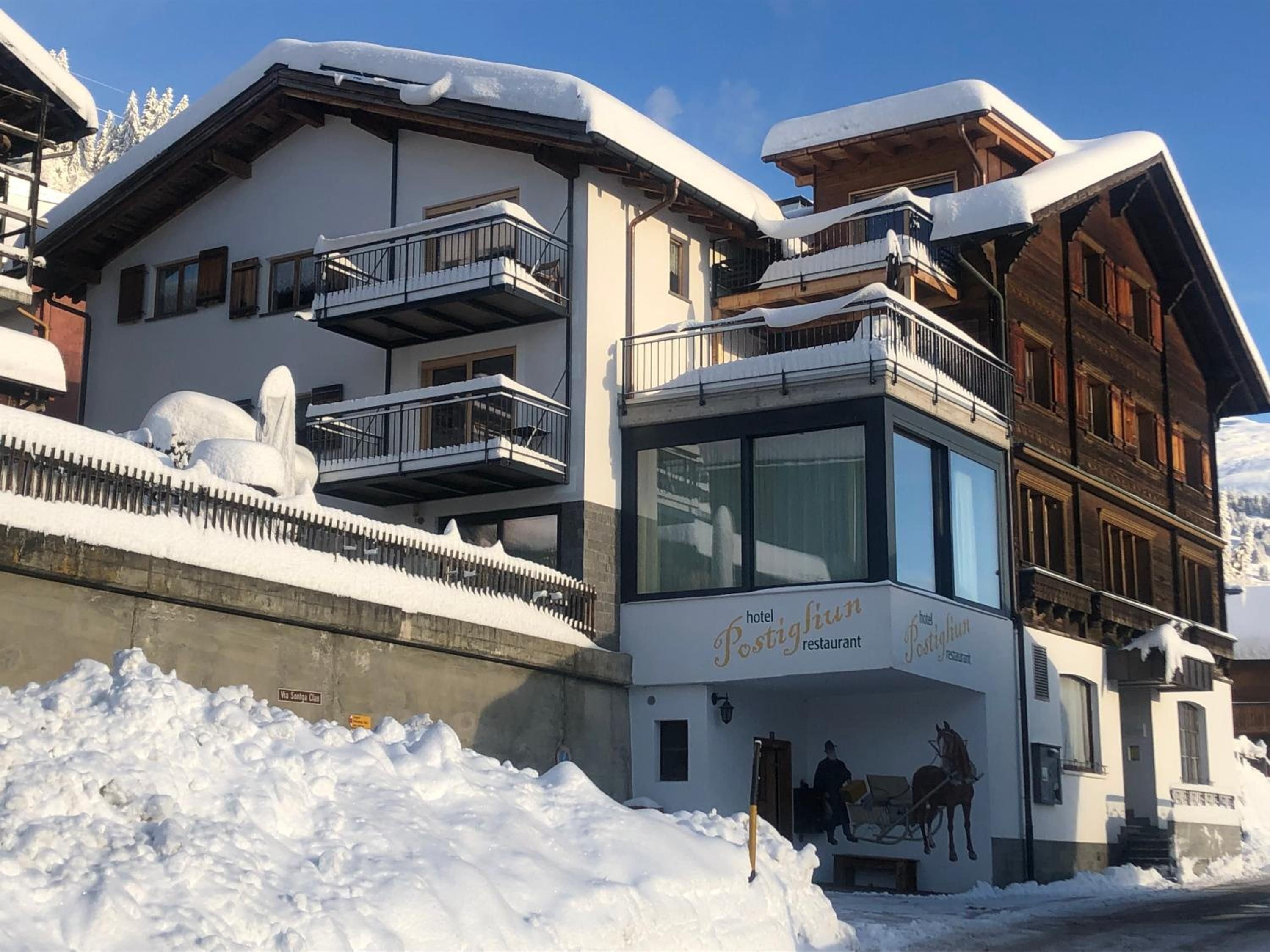 Un hôtel doté d’un restaurant au rez-de-chaussée, de balcons et dont l’extérieur est recouvert de neige.