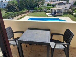Ein Balkon mit Tisch und Stühlen, ein Schwimmbecken und Blick auf die Umgebung.