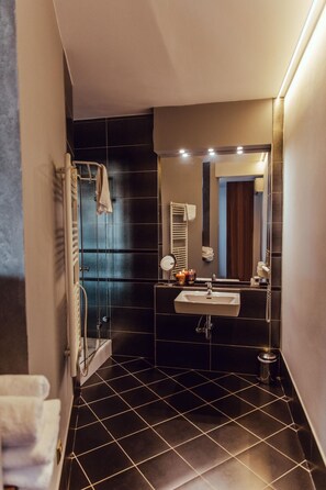 A modern bathroom with a glass shower enclosure, a sink with a mirror, and a toilet.