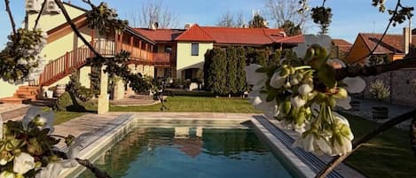 A pool area with a clear view of a building with a red roof and a staircase leading to a balcony.