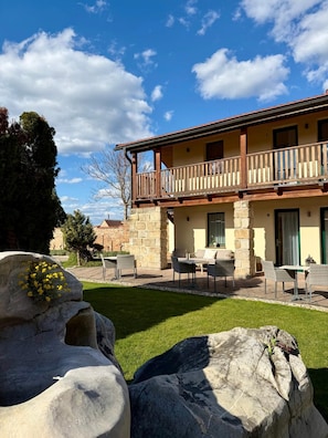 A two-story building with a balcony, stone walls, and outdoor seating.