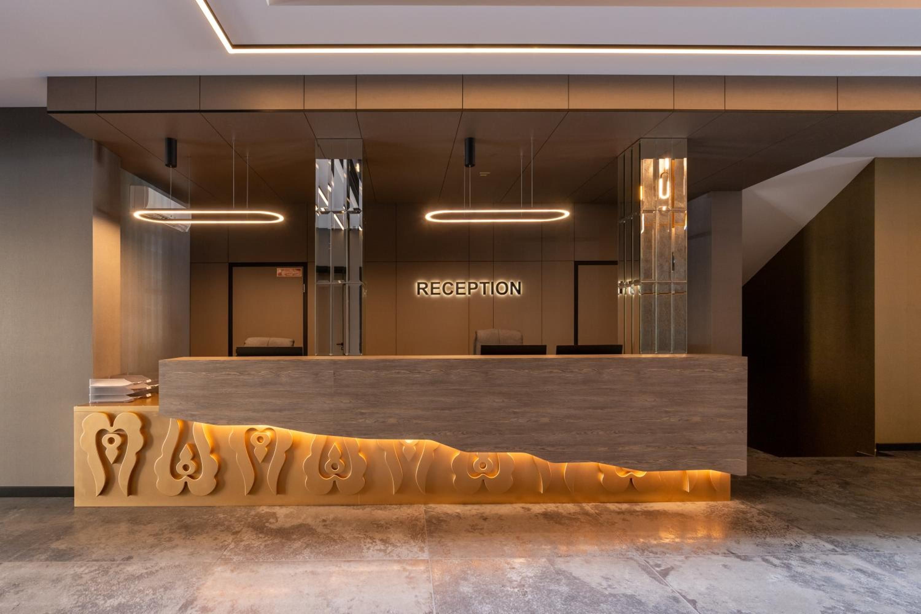 Un mostrador de recepción de diseño moderno, con detalles de madera y una escultura iluminada de estilo único.