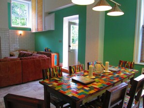 Un comedor con una mesa y sillas coloridas, un sofá y una ventana con persianas.