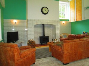 Una sala de estar con chimenea, un reloj y un televisor.