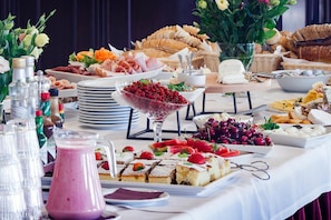 Una mesa de buffet con diversos alimentos, como frutas, quesos y pasteles.