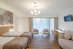 Habitación de hotel con tres camas, un escritorio, una silla y un televisor.