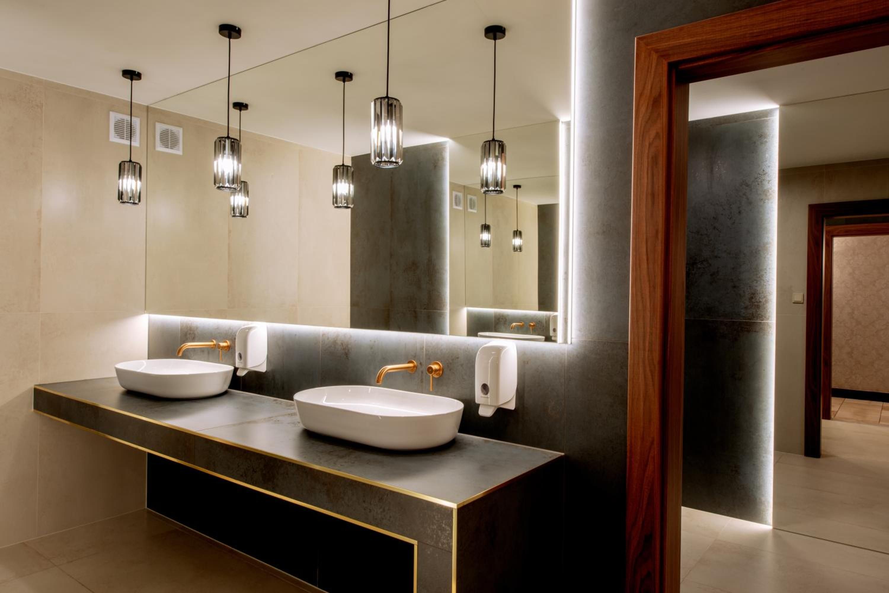 Ein modernes Badezimmer mit zwei Waschbecken, einem großen Spiegel und Pendelleuchten.