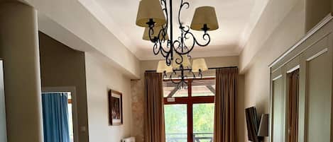 Amplia sala de estar con un sofá grande, una araña y vistas a través de una ventana con cortinas.