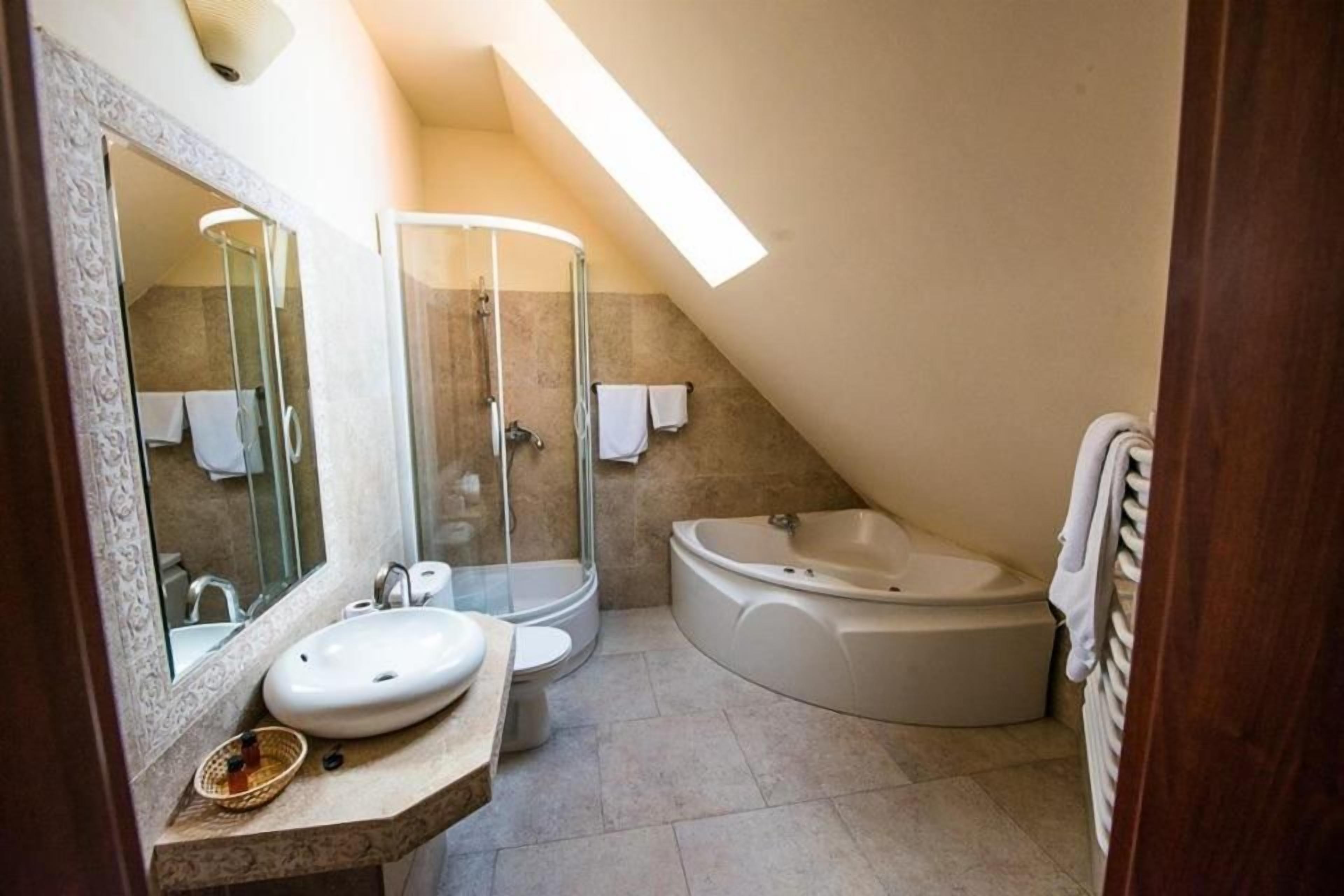 Et badeværelse med et fritstående badekar, en glasafskærmet bruseniche, en vask og et toilet.
