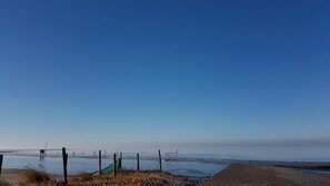 A coastal view with a clear sky, a sandy beach, and a fence. - Goode Wind (Norden)