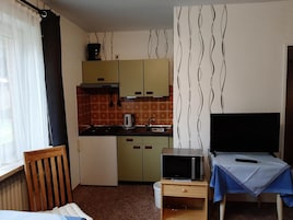 A compact kitchen with a microwave, kettle, and sink.