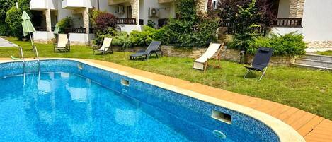 A swimming pool with lounge chairs and a stone wall.